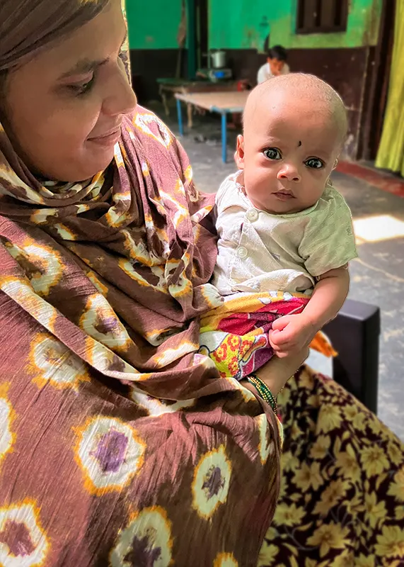 A woman holds an infant on her hip.
