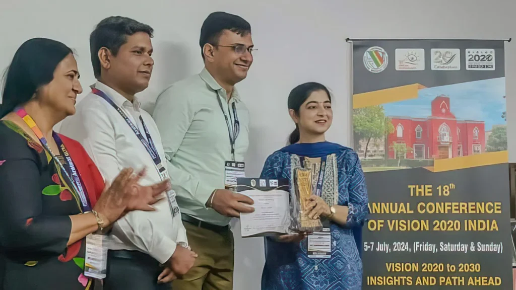 A group of four people stand smiling. One of the men holds a certificate.