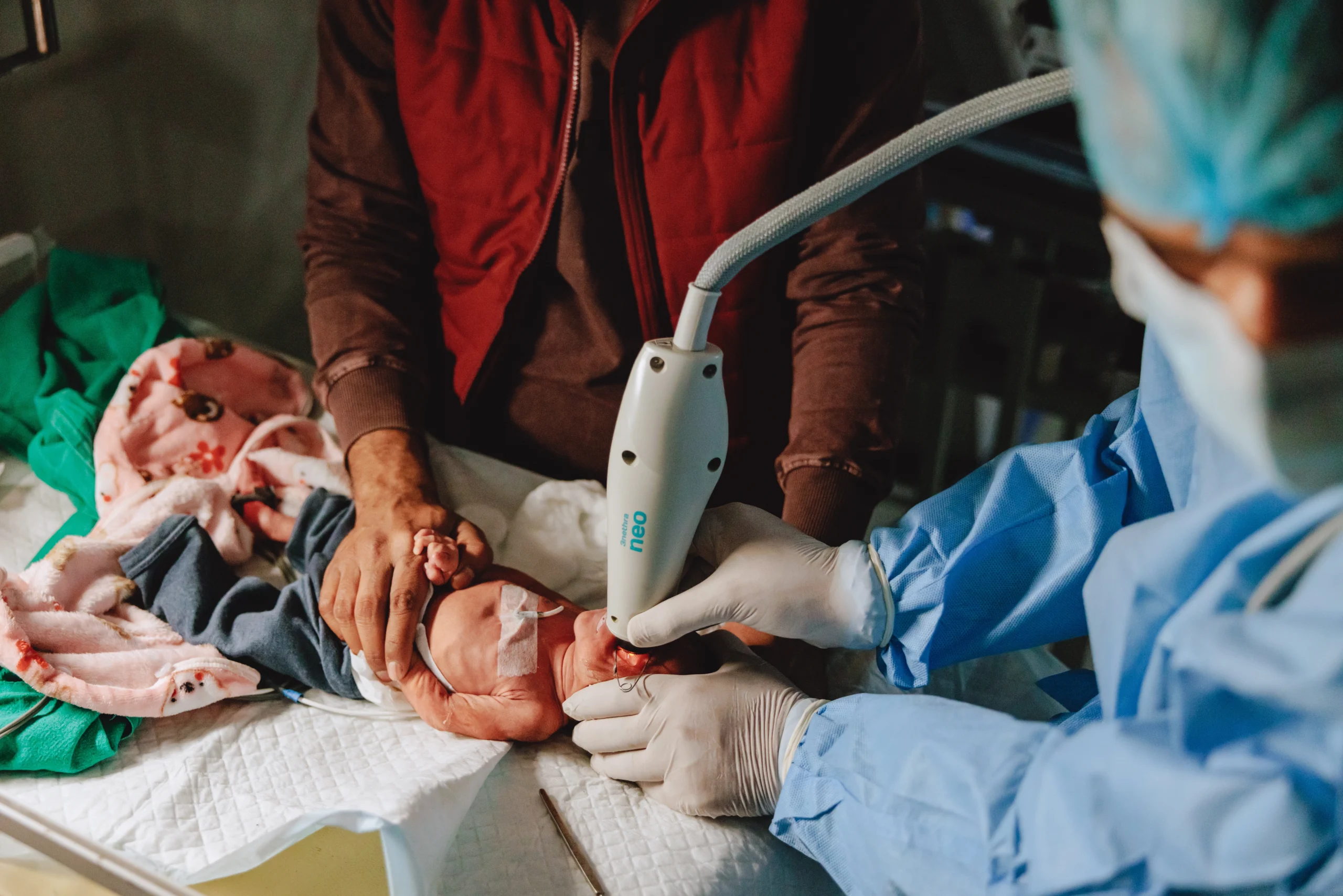 Doctors hold a screening device over the eye of a premature baby.