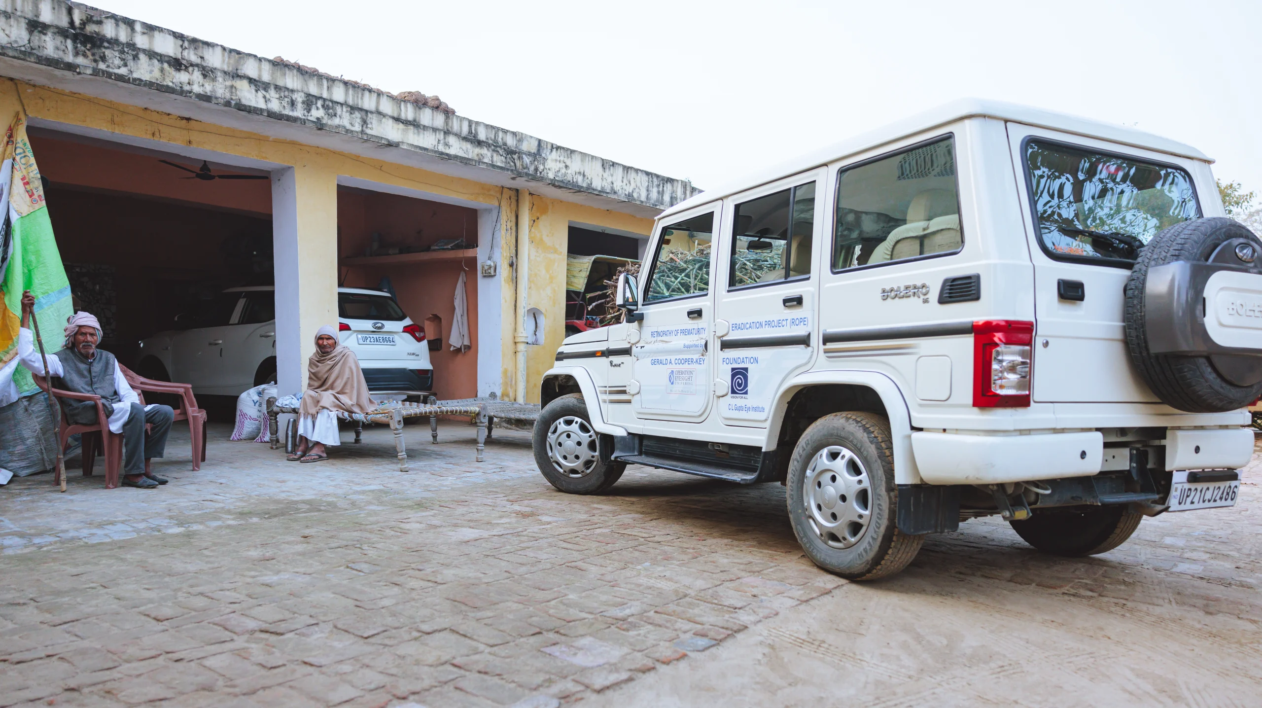 A jeep with logo markings on the side is parked in front of a building