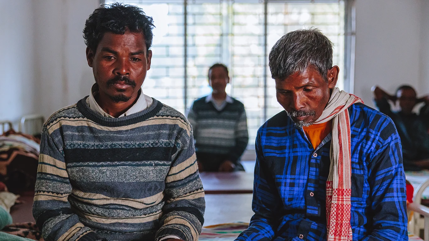 A man stands in front of his home with his two daughters.|
